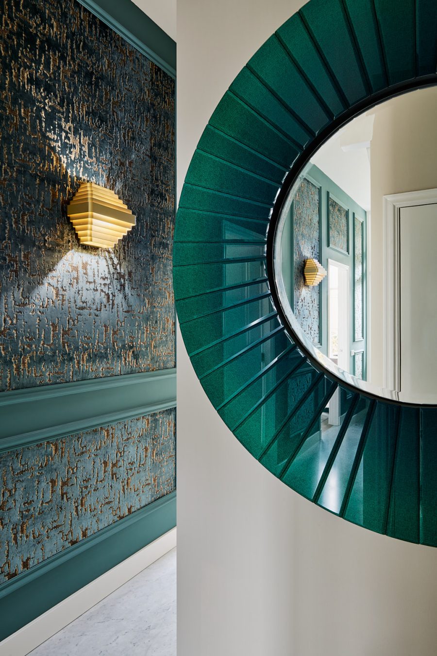 klassieke hal met blauwe muren, blauw fluweel behang in de lijsten, gouden wandlampen en een groene glazen spiegel