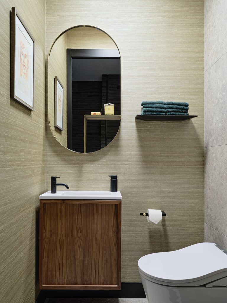 toilet met licht groen behang, ovale gouden spiegel en notenhouten wastafel