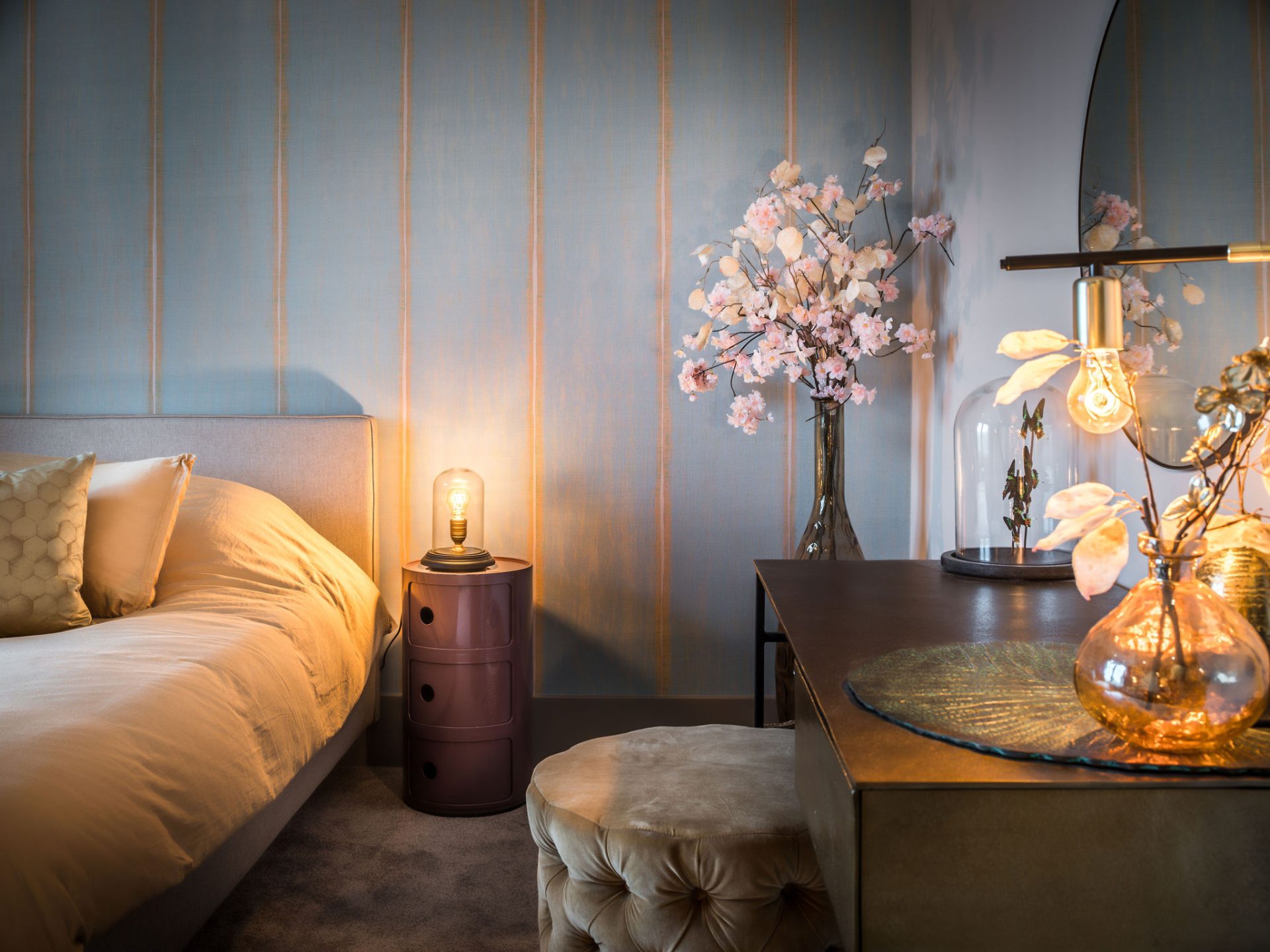 meidenkamer met blauw behang, roze nachtkastje, brons stalen bureau met beige fluwelen poefje en een ronde spiegel