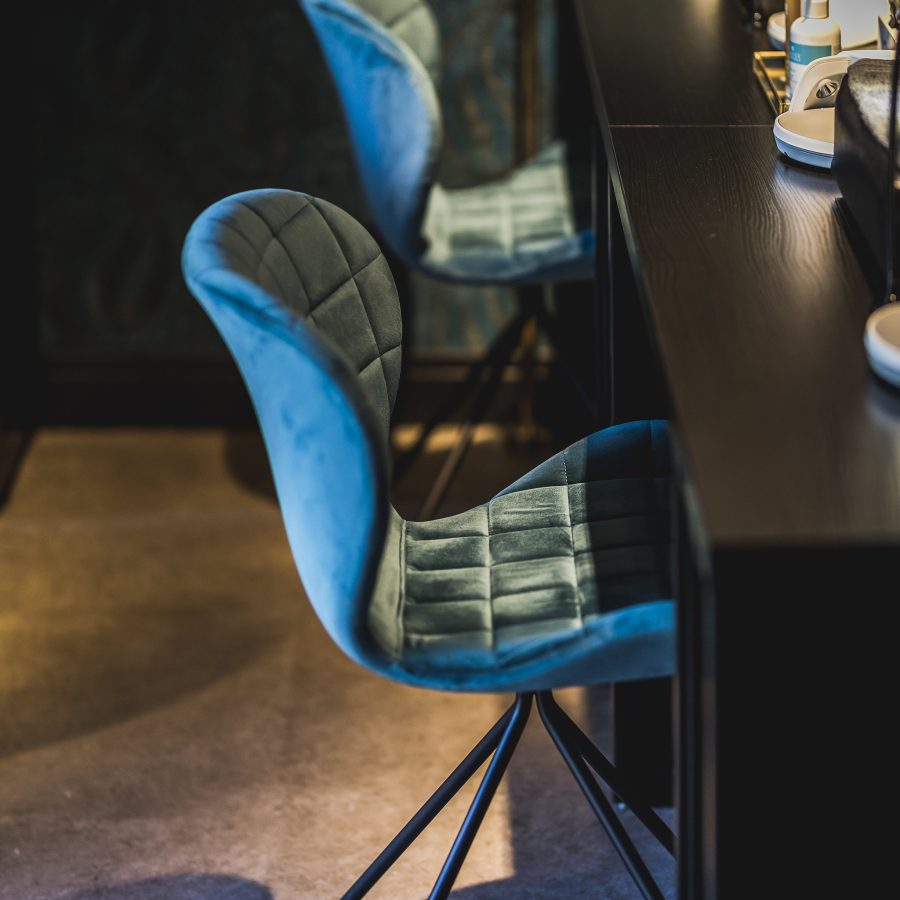 Blauwe fluwelen bureaustoeltjes in een beautysalon voor een nagel tafel.