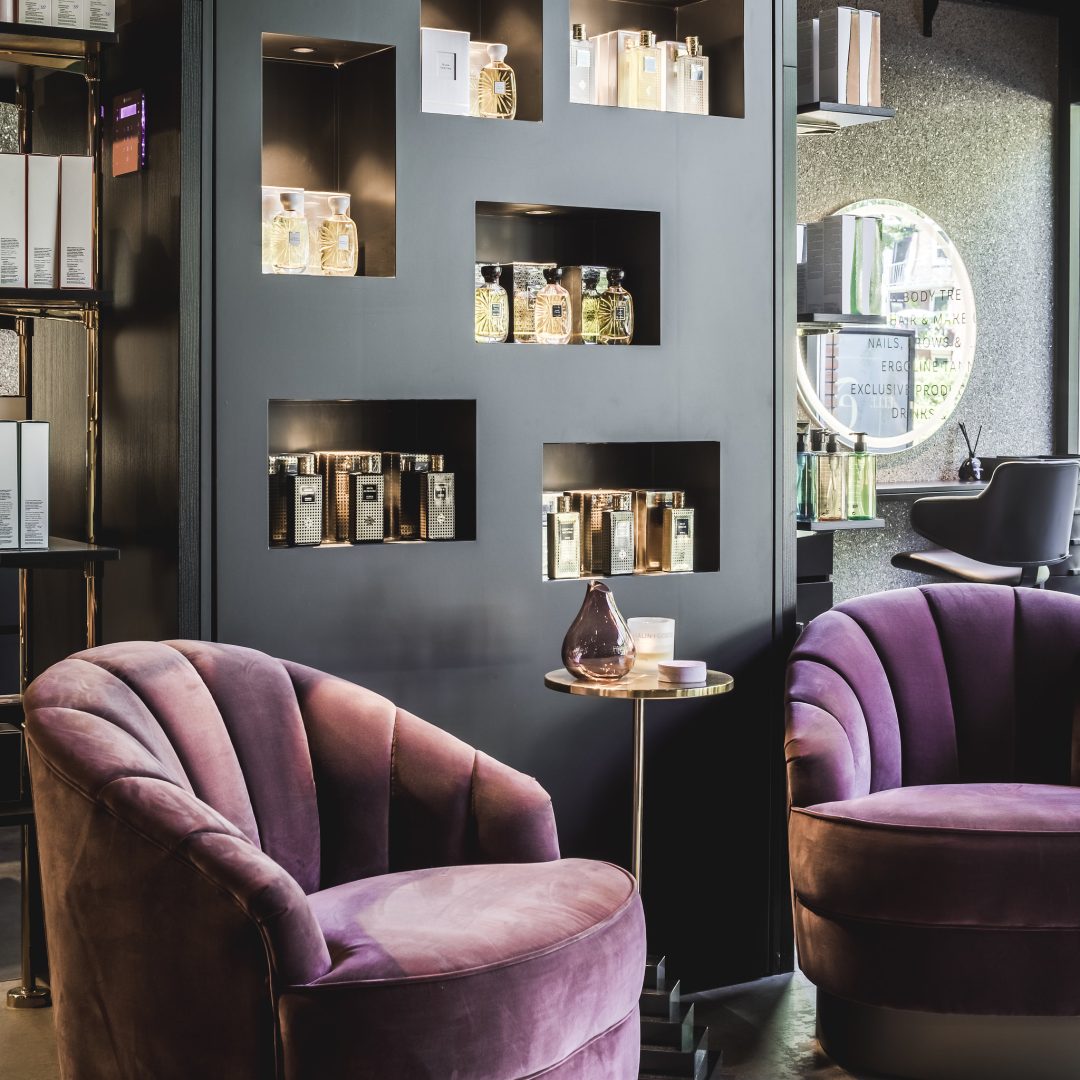 fluwelen paarse ronde fauteuils voor een zwarte vakken kast in een beuaty salon.