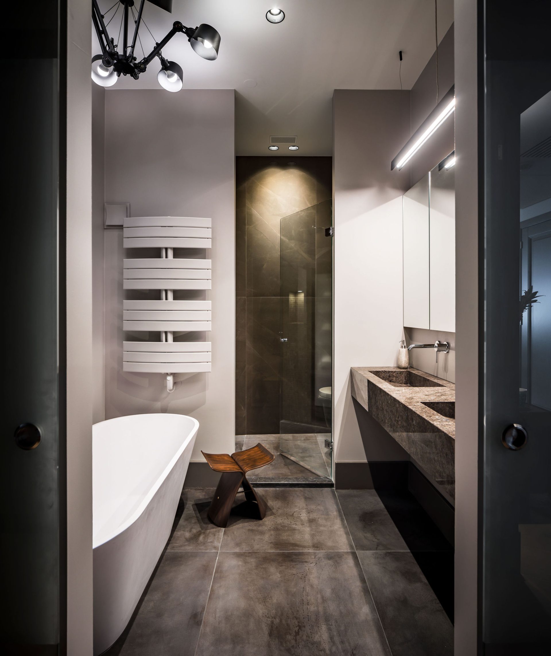 badkamer met donkerbruine marmeren tegels en wastafel, wit vrijstaand bad