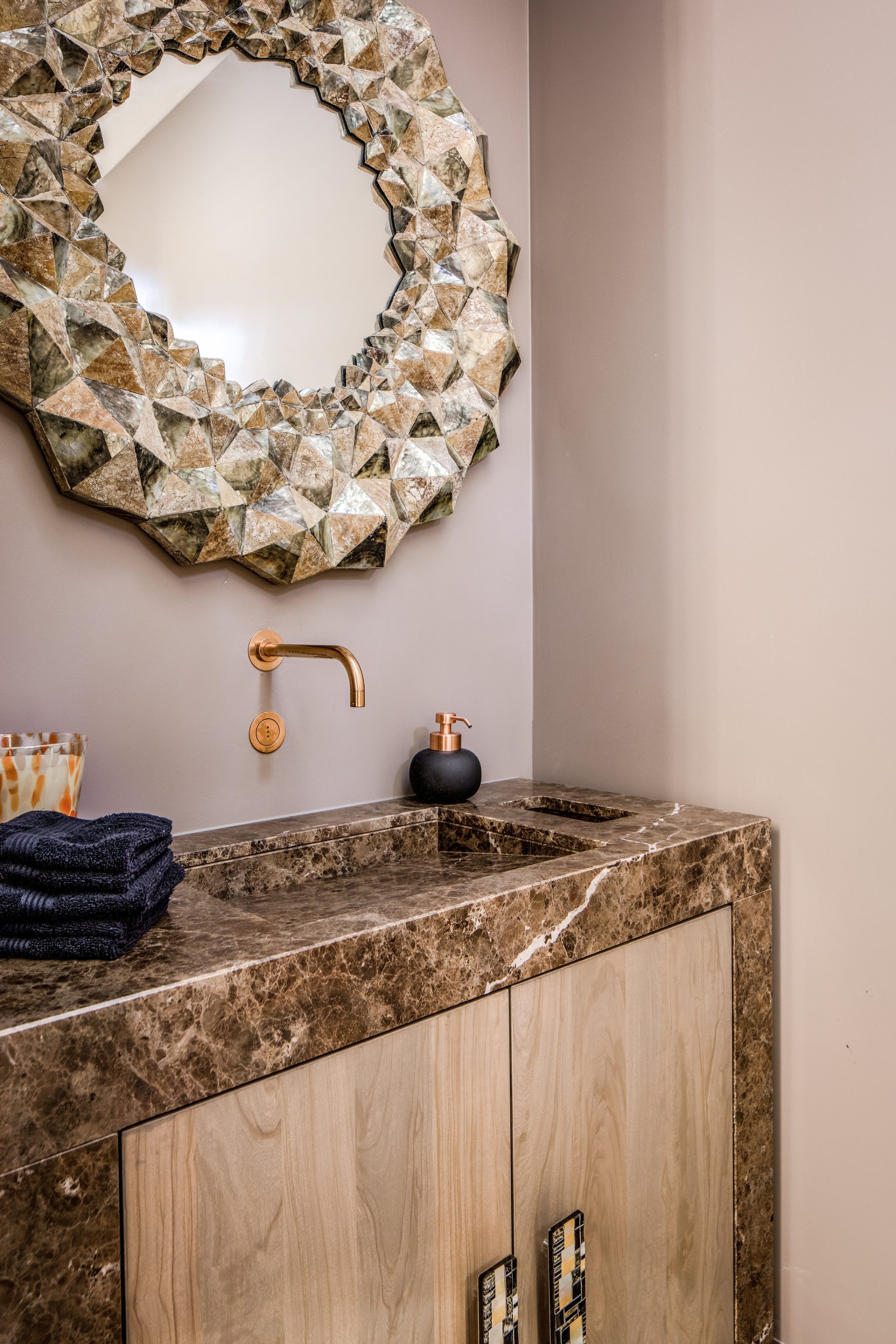 Toilet wastafel met bruin marmer blad, brons sanitair en een unieke spiegel